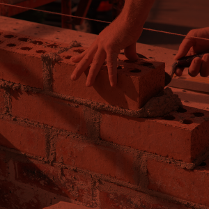 Bricklayer spreading mortar and placing brick