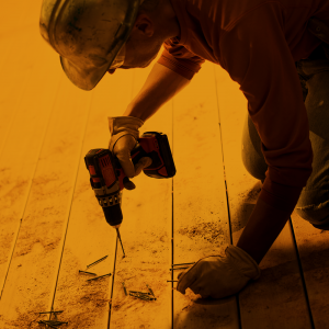 Carpenter drilling screws into wooden floor