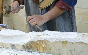 Stonemason chiseling a cube of sandstone